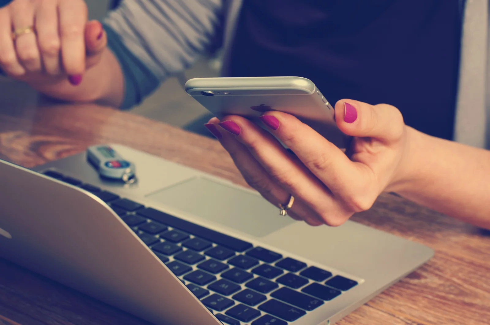 Blog, hier eine Dame mit Handy und Notebook am Tisch sitzend zu sehen