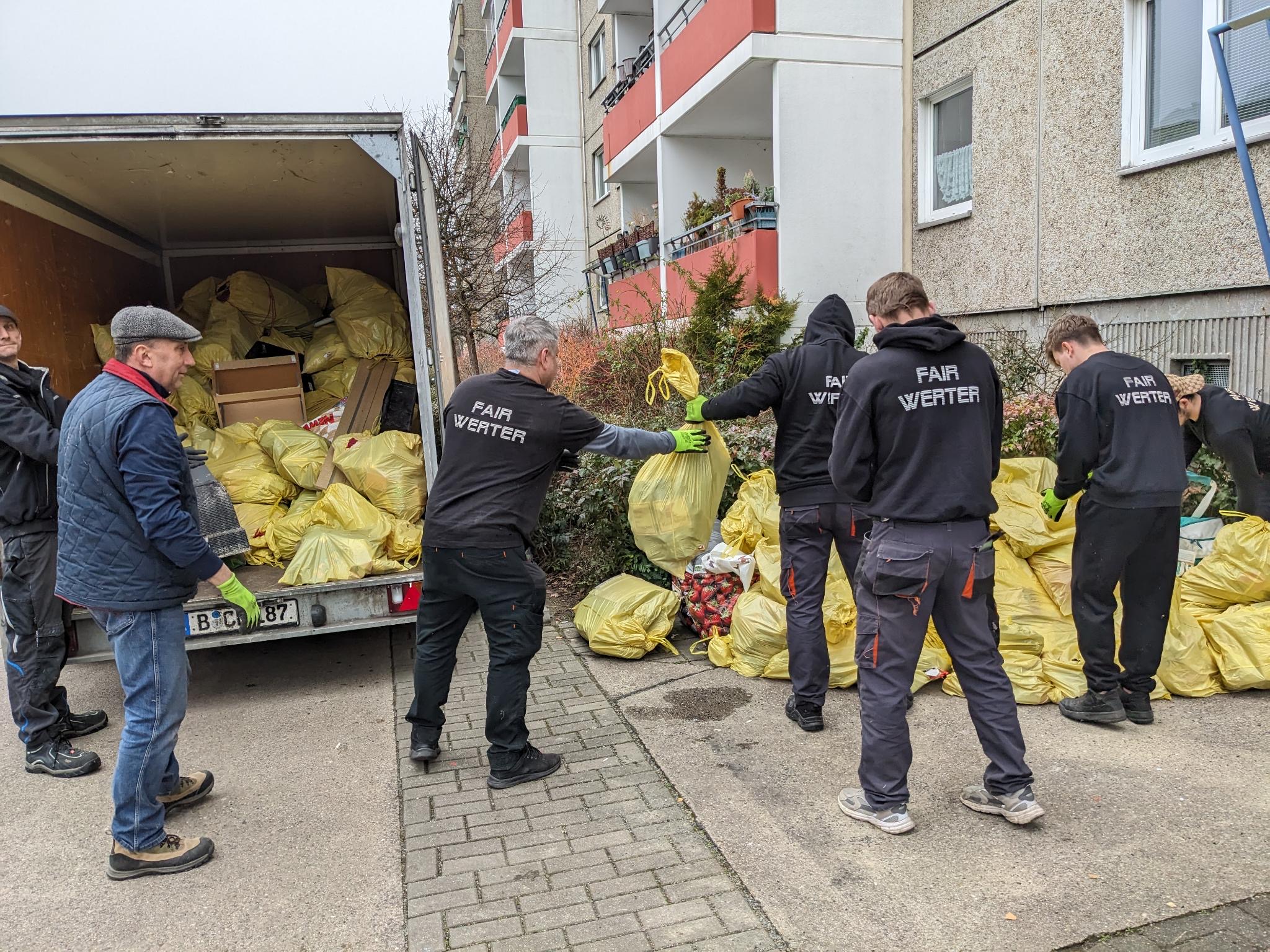 Mitarbeiter beim Transorter beladen mit vielen gepackten Müllsäcken
